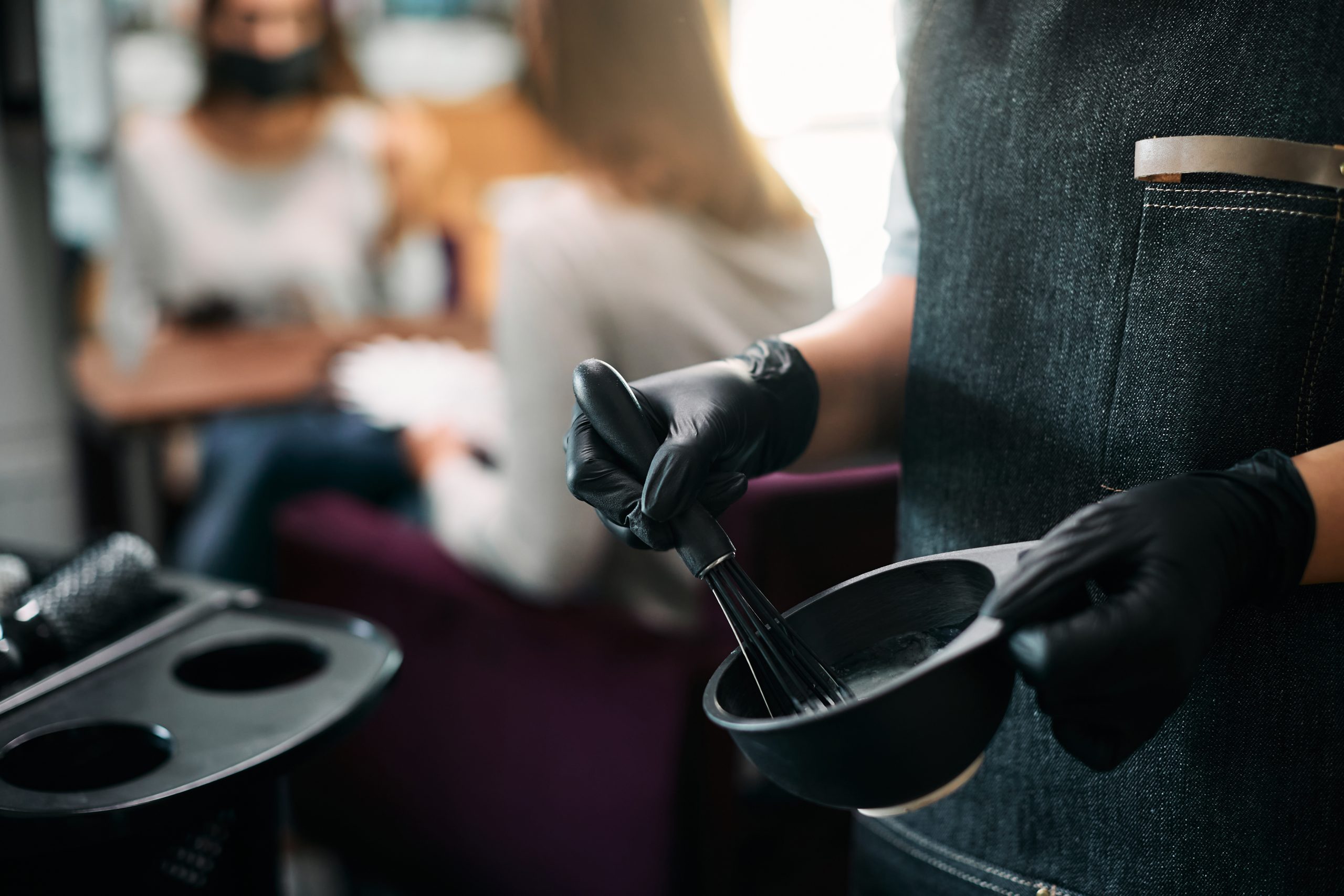 Close-up of hairstylist mixing hair dye while working at the salon.